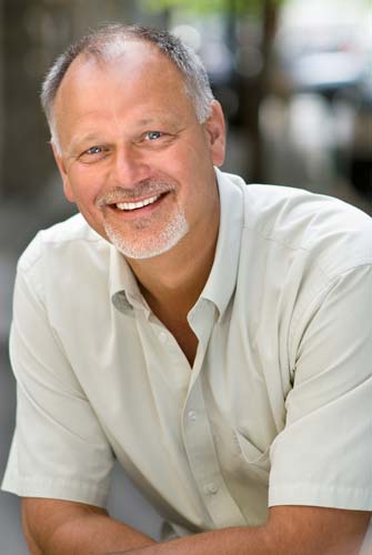 Shows a professional headshot of a business coach, man, casual, half body, outside
