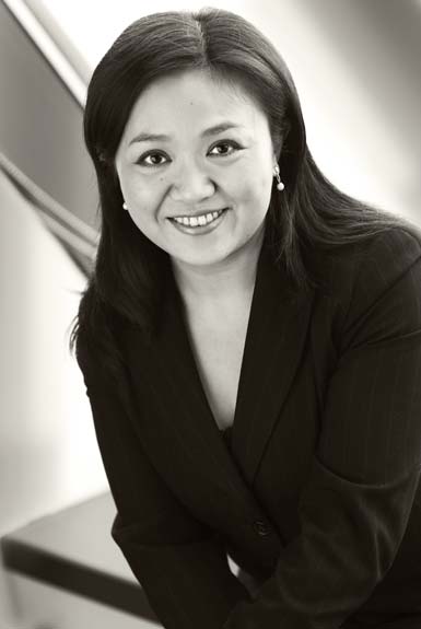 Shows a professional business headshot of a woman, formal, suit, half body, ambient background