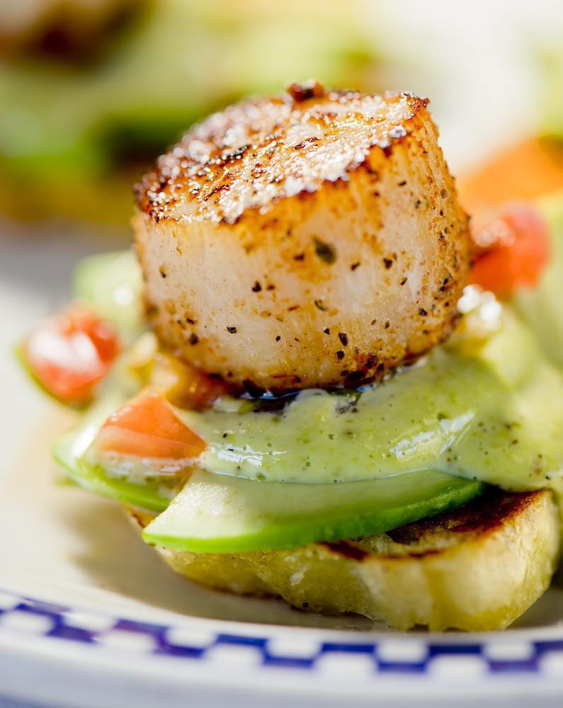 Scallop on toast with sliced veggies and sauce