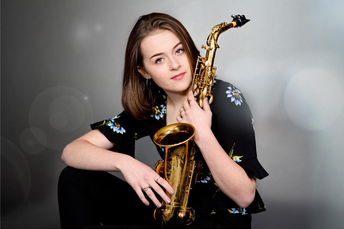 Young woman with a saxophone sitting