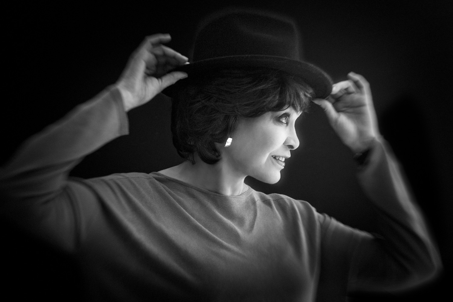 Woman trying on hat in black and white